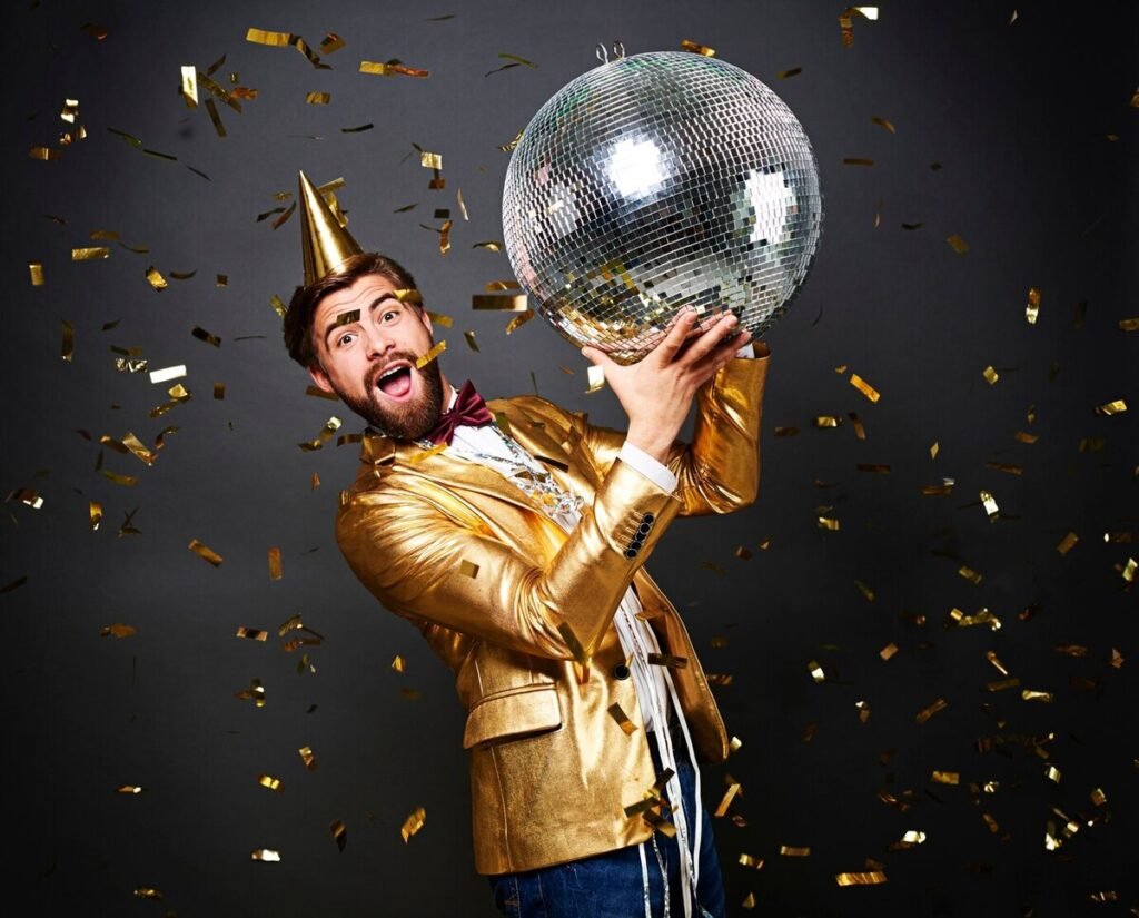 A man with a yellow suit having anniversary celebration while holding a disco ball
