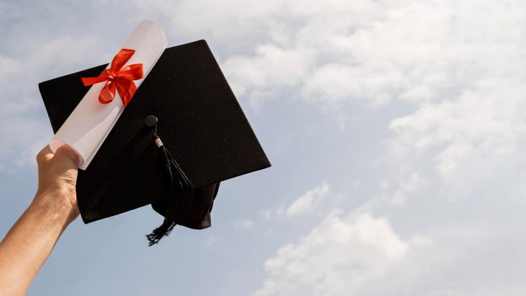 A person holding graduation diploma and hat in the air