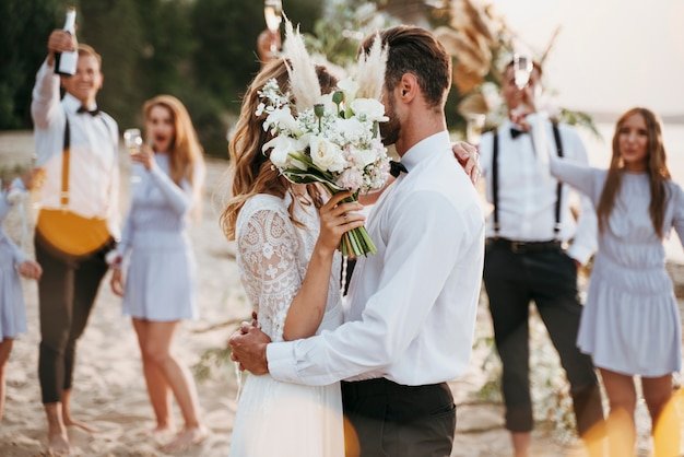 Bride and groom having their wedding with guests on a beach 