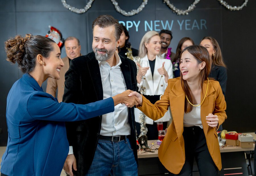 woman shakes hands to her colleague at new year party