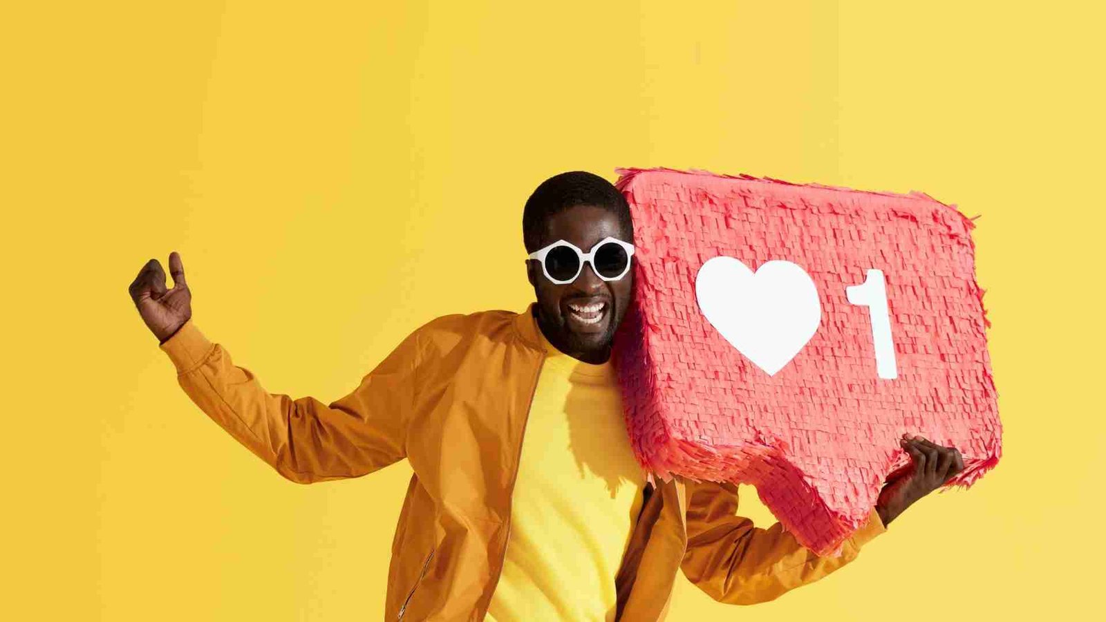 Happy man holding a large Instagram like icon, representing the excitement of gaining likes, real or purchased.