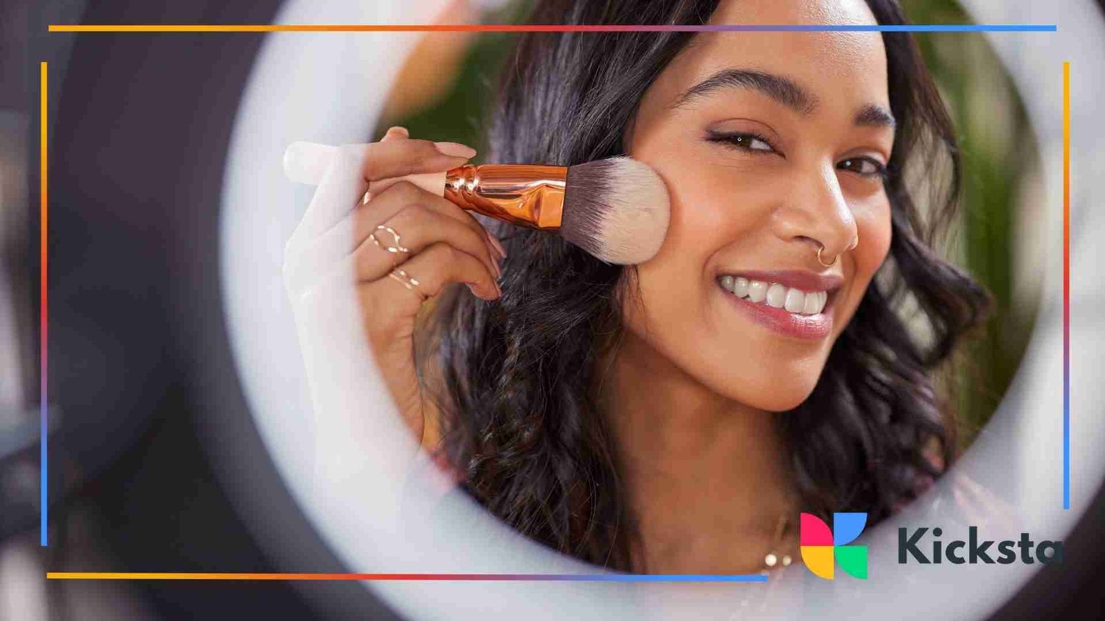 Woman applying makeup with a brush while smiling at the camera.