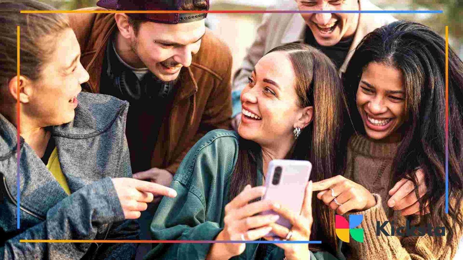 Group of friends laughing together while looking at a phone.