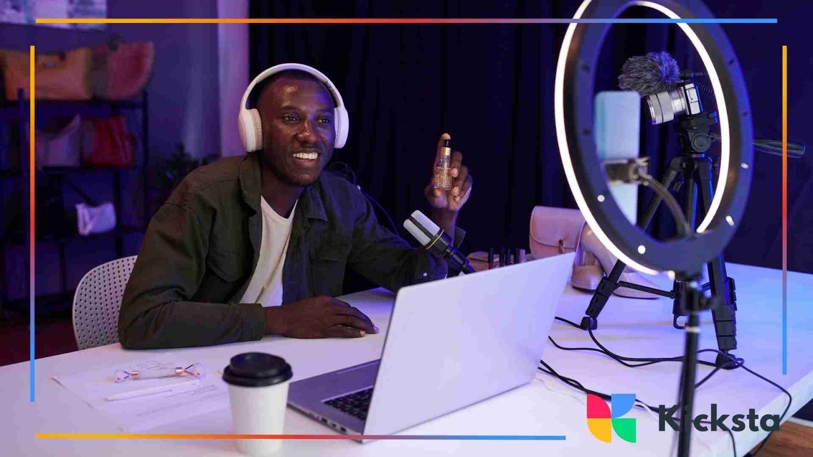 Man wearing headphones livestreaming at a desk with a laptop, ring light, and recording equipment.