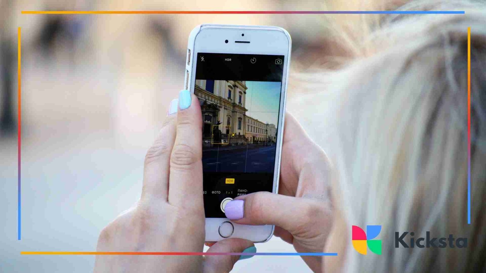 Person holding a smartphone and taking a photo of a building in an urban outdoor setting.
