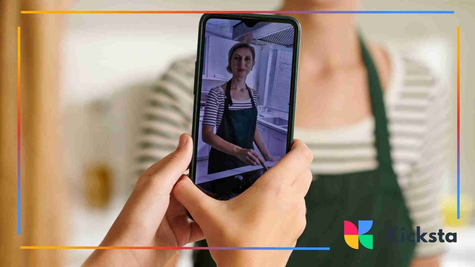 Hands holding a smartphone that records a woman in an apron preparing food in a kitchen.