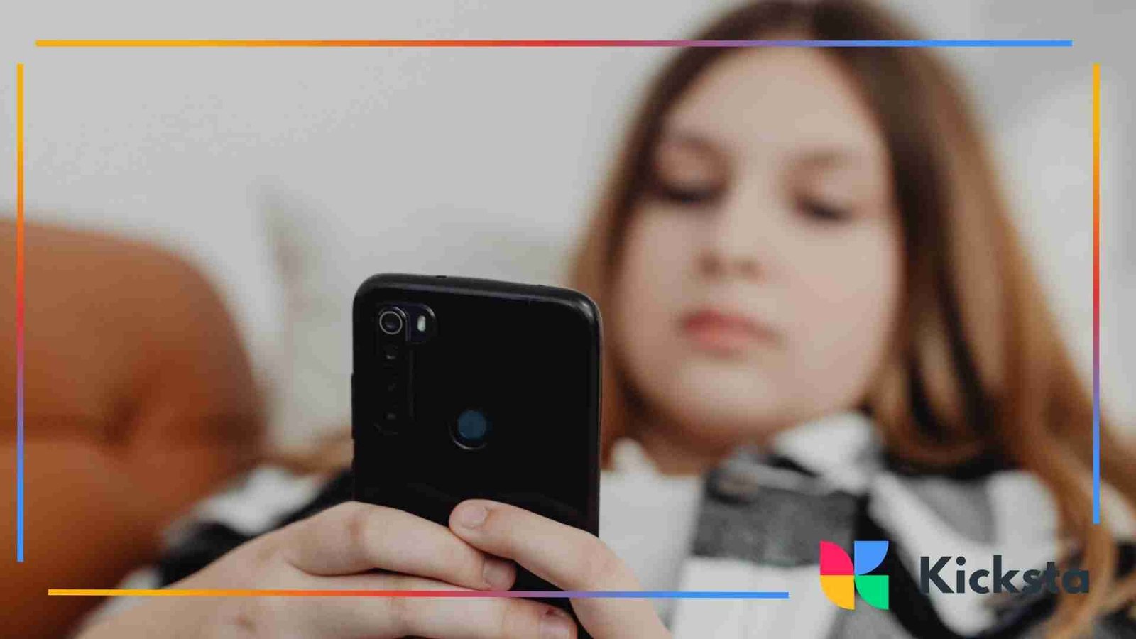 A girl holding a black phone.