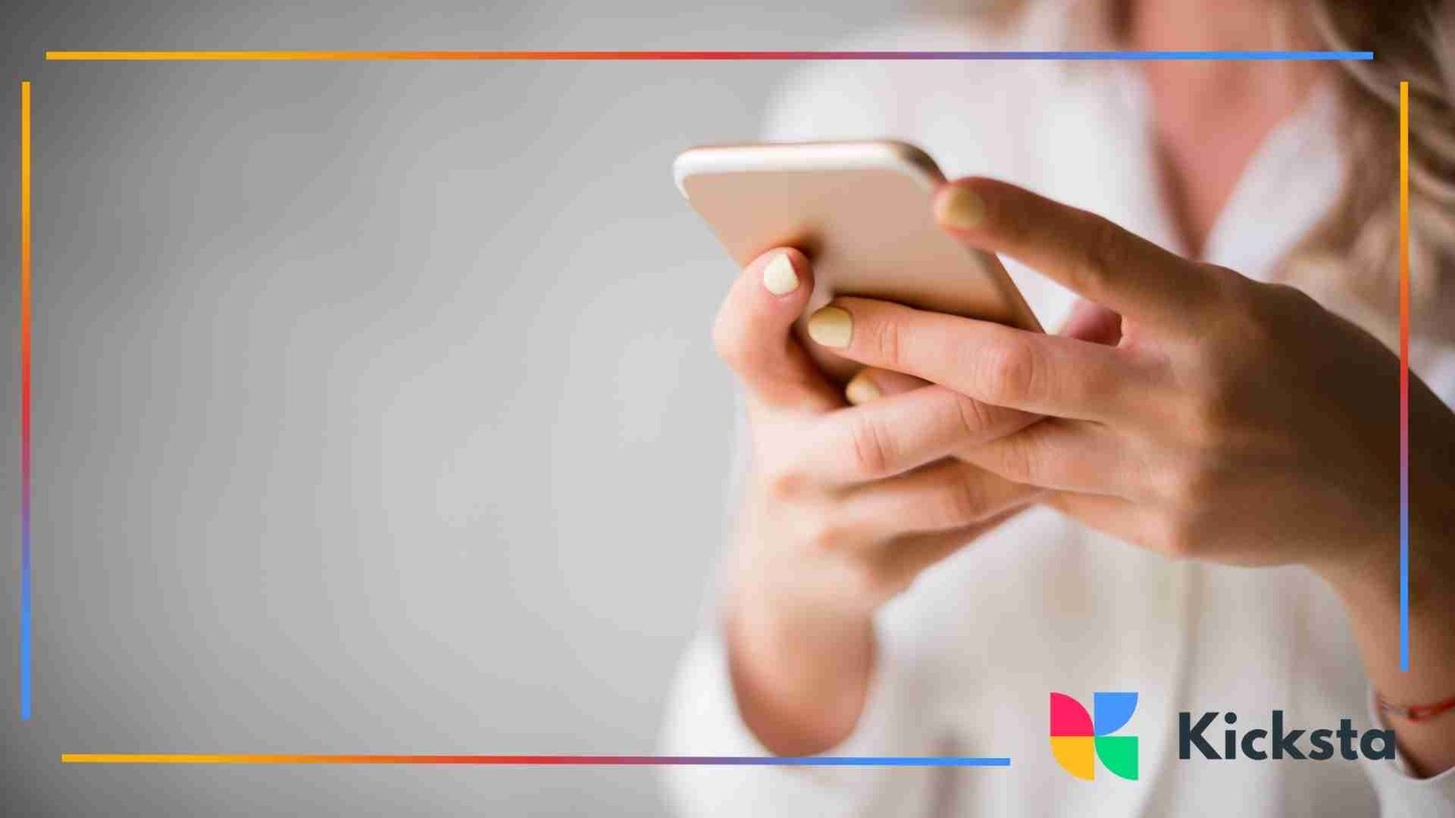 Close-up of a woman holding a smartphone with both hands, typing on the screen against a blurred gray background.