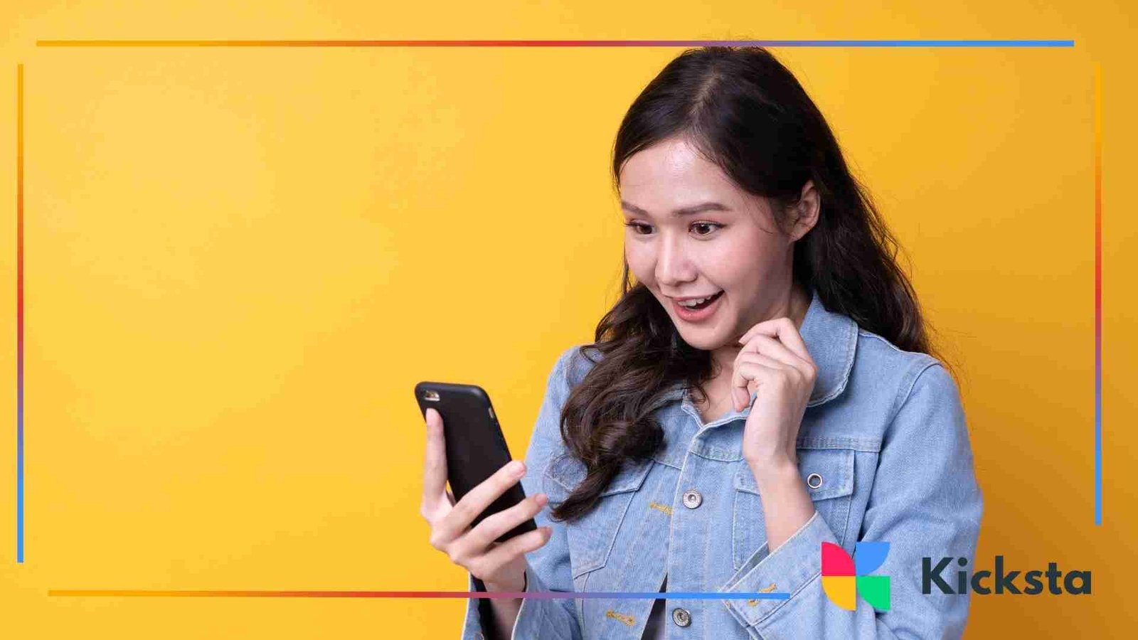 A woman holding a phone and smiling n front of a yellow wall
