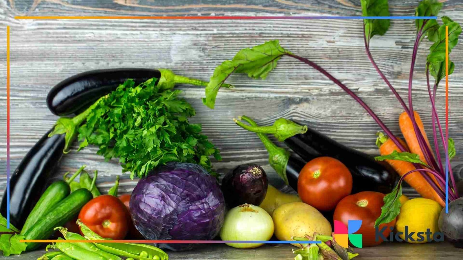 Assortment of fresh vegetables including eggplants, tomatoes, cabbage, carrots, parsley, cucumbers, and onions arranged on a rustic wooden surface.