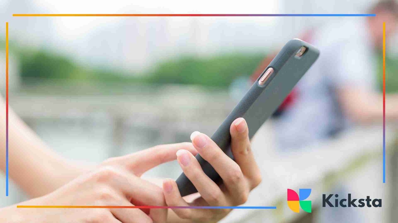 Hands holding a smartphone outdoors, with a blurred city background.