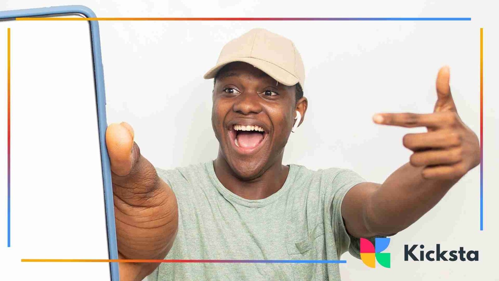 Smiling man wearing a cap and earbuds pointing excitedly at a smartphone with a blank screen.