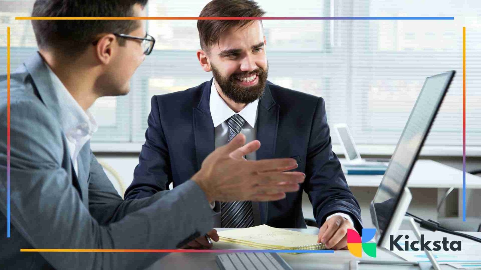Two professionals discussing data and smiling while reviewing information on a desktop computer.