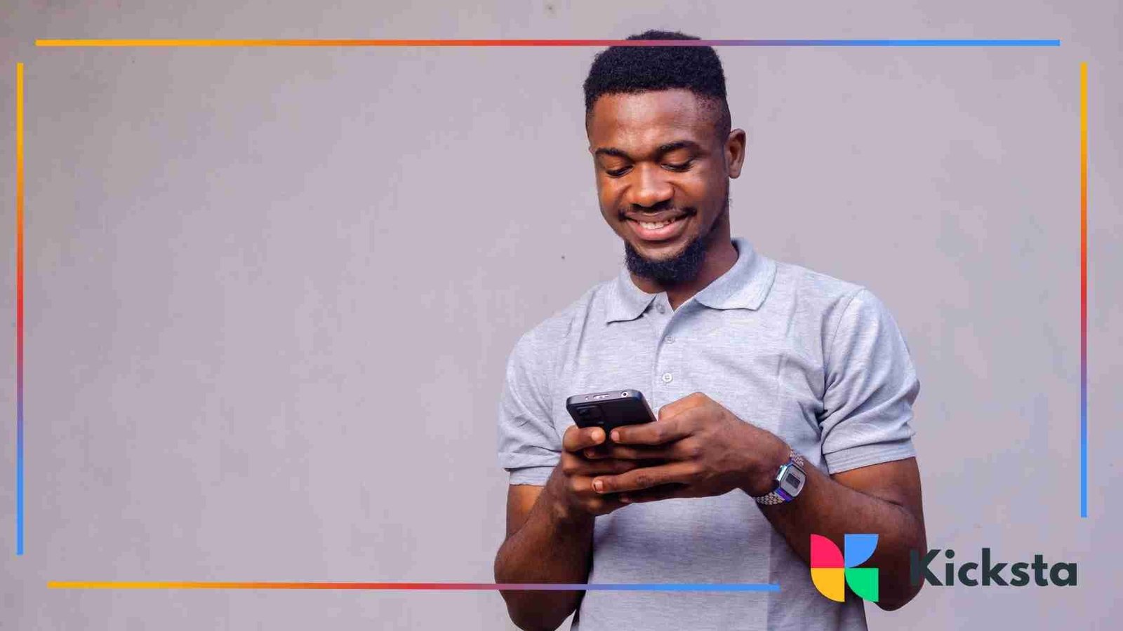 Man smiling while typing on a smartphone against a plain background.
